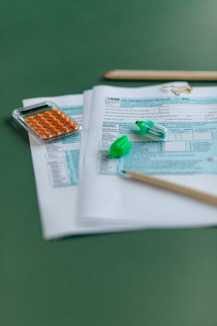 Close-up of tax documents with calculator on a green table, ideal for finance themes.